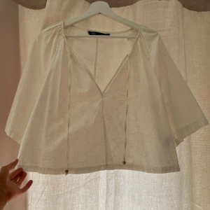 Vit blommig blus från Zara - Säljer en vit blus från Zara i storlek L med diskret blommigt mönster. Blusen har v-ringning, korta ärmar och två smala knytband framtill.💗