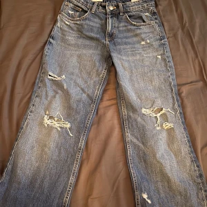 Jeans med hål - Säljer ett par blå jeans från Zara i storlek 36 med snygga slitningar och hål på benen. 