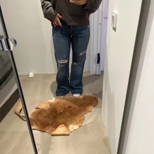 Blå jeans med raka ben och hål - Snygga blå jeans med slitningar och hål på benen för en cool, avslappnad look. Raka ben och klassisk femficksmodell. Jeansen har en mörkblå tvätt och är tillverkade i robust denim. Perfekta för dig som gillar en trendig streetstil.