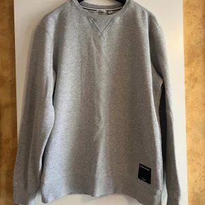 Grå sweatshirt från Björn Borg - Säljer en riktigt snygg grå sweatshirt från Björn Borg i storlek S. Tröjan har rund hals, långärmade ärmar och en svart patch med logga nedtill. 