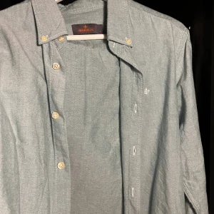 Ljusgrå skjorta från Morris, storlek L - Säljer en stilren ljusgrön skjorta från Morris i storlek L. Skjortan har klassisk krage, knappar framtill och diskret broderad logga på bröstet. Tillverkad i mjuk bomull och har långa ärmar. 