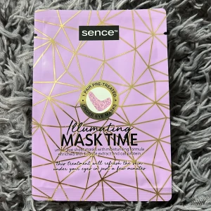Sence Illuminating Mask Time ögonmask - Lila förpackning med guldmönster innehållande ett par under eye sheet masks. Maskerna är berikade med lakritsextrakt och havreprotein för återfuktning och lyster. Vegansk formula, 6 ml. Perfekt för att pigga upp huden under ögonen.