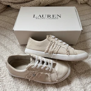 Beigea sneakers från Ralph Lauren - Säljer dessa snygga beigea sneakers från Ralph Lauren i textil med fransade detaljer och vita snören. Modellen heter Janson Fray och är dem skönaste skorna jag haft! Loggan finns både under och på sidan av skon🌸 (modellen i beige är slutsåld överallt och är köpt från Ralph Laurens egna sida)