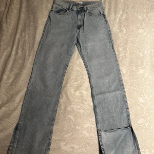 Ljusblå raka jeans från H&M, strl 36 - Ljusblå jeans från H&M. Hög midja och femficksdesign med dragkedja och knapp framtill. Jeansen är raka/utsvängda nertill med slits.