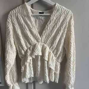 Beige omlottblus med volangdetaljer - Säljer en superfin beige omlottblus med v-ringning och volangdetaljer i midjan.💕