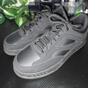 Svarta sneakers från YOURTURN - Säljer ett par helsvarta sneakers från YOURTURN med chunky sula och rund tå. Skorna har snörning och är tillverkade i syntetmaterial med diskreta sömdetaljer och perforeringar på tån. Perfekta för en clean och stilren look.