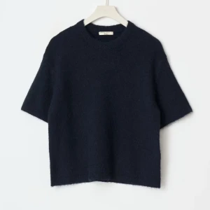 Mörkblå stickad tröja från Gina tricot - Mysig mörkblå stickad tröja från gina tricot med kort ärm och rund halsringning. Tröjan har en rak, lite boxig passform och är tillverkad i ett mjukt material som känns lyxigt mot huden. Perfekt för lager-på-lager under kyliga dagar.