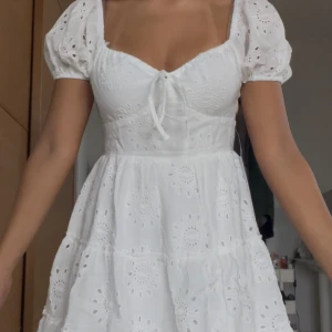 Vit kortklänning från Princess Polly - Supersöt vit kortklänning från Princess Polly med broderade blommor, puffärmar och knyt framtill. Klänningen har omlottkänsla, markerad midja och volangig kjol. Köptes till studenten men hittade en annan. Har aldrig använts. Kom med två små bruna prickar som inte syns när man har på sig den. Skriv om ni vill ha mer bilder 💗😊