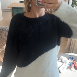 stickad tröja vila  - Supermjuk och fluffig tröja från Vila i svart och vitt. Tröjan har lång ärm och coolt sneddelat färgblocksmönster. Perfekt för dig som gillar en mysig och trendig look. Rund halsringning och relaxed passform.