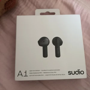 Sudio A1 - Sudio A1 är trådlösa open-ear hörlurar med IPX4 vattentålighet, upp till 6,5 timmars batteritid och tydlig röstkvalitet. Produkten är i originalförpackning, helt oöppnade, perfekt för dig som söker smidiga och stilrena hörlura.