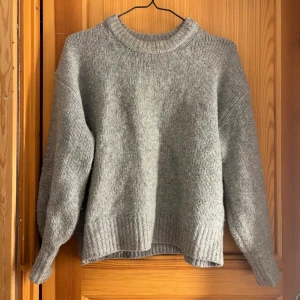 Grå stickad tröja från BikBok XS - Mysig grå stickad tröja från BikBok i storlek XS. Tröjan har en klassisk rund halsringning, ribbade muddar och lång ärm. Perfekt för lager-på-lager och chill dagar. Enkel och stilren design som funkar till allt.