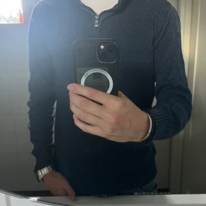 Marinblå stickad tröja Carl William - Säljer en marinblå stickad tröja från Carl William med ribbad krage och axelparti. Tröjan har half zip-dragkedja och långa ärmar. Perfekt för kyliga dagar och snygg till jeans eller chinos.