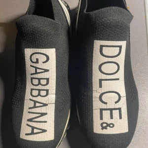 Dolce & Gabbana svarta sneakers - Svarta slip-on sneakers från Dolce & Gabbana med tydlig logga på ovansidan och sidorna. Storlek 41 säljs i samma skick som på bilderna fast pris kolla gärna mina andra annonser 