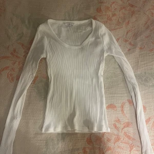 Vit ribbad långärmad topp Lindex - Säljer en vit ribbad långärmad topp från Lindex. Toppen har en rundad halsringning och är figurnära i modellen.