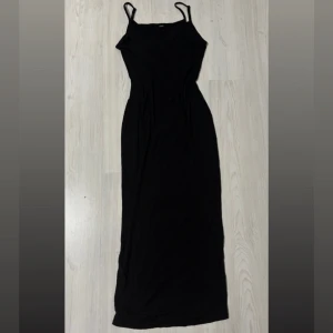 Svart långklänning med smala band SHEIN - Svart långklänning med smala axelband och figurnära passform. Enkel och stilren design som ger en snygg siluett. Figurnära som ger en snatched look! En elegant klänning som är lätt att matcha med accessoarer.