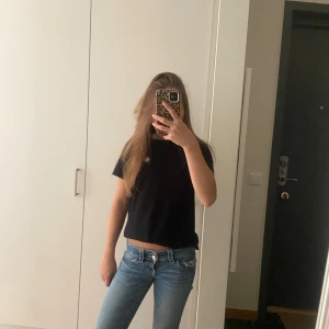 Blå bootcut jeans låg midja - Säljer ett par klassiska blå jeans med bootcut och låg midja. Jeansen har en snygg tvätt och sitter tajt upptill med utsvängda ben. Perfekta för dig som gillar en retro vibe och vill ha ett par jeans som sticker ut lite extra.