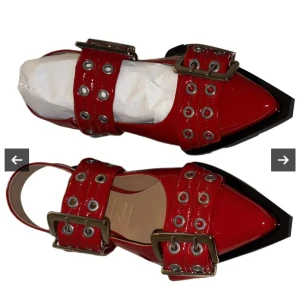 Röda sandaler från GANNI - Snygga röda lackläder sandaler från GANNI med spetsig tå och breda remmar dekorerade med silverfärgade nitar och stora metallspännen. Oanvända, äkta, med orginal förpackning, dustbag etc. 