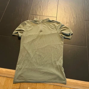 Grön rid-t-shirt med half zip - Snygg grön rid t-shirt från Equipage med korta ärmar och halv dragkedja vid halsen. 