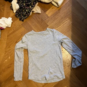 Ljusgrå långärmad basictröja - Enkel och stilren ljusgrå långärmad tröja i mjuk bomull. Perfekt för lager-på-lager och funkar till allt. Tröjan har rund halsringning och en rak passform som sitter skönt på kroppen.