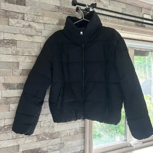 Svart pufferjacka från 157, stl S - Säljer en svart pufferjacka från 157 i storlek S. Jackan har hög krage, dragkedja framtill och två sidofickor. Den är quiltad och har en boxig, lite oversized passform som är perfekt för kyliga dagar.