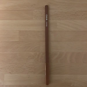 CAIA Lovisa läppenna brun - Snygg läppenna från CAIA i nyansen Lovisa. Pennan har en varm brun färg och klassisk pennform med lock. Perfekt för att definiera läpparna och skapa en naturlig look. Enkel att applicera och passar till många olika läppstift. Vässad någon gång. Fortfarande mycket kvar.
