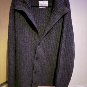 Grå ribbstickad kofta från Jack & Jones - Mysig grå ribbstickad kofta från Jack & Jones med stora knappar framtill och bred krage. Perfekt för lager-på-lager och chill höst- eller vinterstil. Klassisk modell med lång ärm och normal passform.