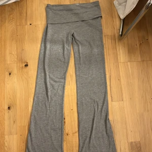 Grå lowwaist bootcut yoga pants Gina Tricot - Grå yoga pants från Gina Tricot i storlek 158/164. Byxorna har bootcut-ben och bred, vikt linning för extra bekväm passform. Tillverkade i mjukt bomullsmaterial med stretch. Perfekta för en chill och avslappnad look.har en liten slitning längst ner på höger ben man det är inget man tänker på! Priset kan diskuteras!☺️