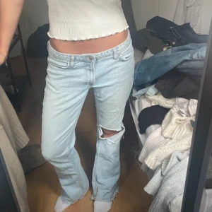 Ljusblå jeans från Zara - Säljer ett par ljusblå jeans från Zara med bootcut passform och slitning vid knät. Jeansen har klassisk femficksdesign, normal midja och är tillverkade i bomull. Perfekta för en avslappnad och trendig look.