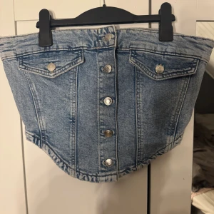 Denim tubtopp med knappar -  tubtopp i ljusblå denim med knappar framtill.