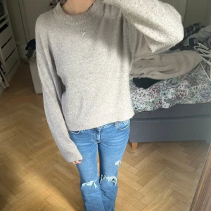 Beige stickad tröja med rund hals - Mysig beige stickad tröja med rund hals och långa ärmar. Tröjan har en loose passform och ribbade muddar vid ärmslut och nederkant. Perfekt att slänga på sig när det är lite kyligt ute. Enkel och stilren design som funkar till jeans eller kjol. Nopprig men kan försöka ta bort innan jag postar!!💓💓