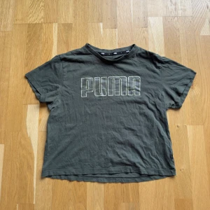 Mörkgrön/militärgrön PUMA t-shirt / träningströja med logga - Snygg mörkgrön t-shirt från PUMA med stor logga framtill. Klassisk passform med korta ärmar och rund hals. Tillverkad i mjuk bomull med lite elastan för extra komfort. Perfekt för en chill och sportig look eller till gymmet 