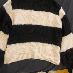 Svartvit randig stickad tröja - Säljer en stickad tröja med breda svarta och vita ränder. Tröjan har långärmade och en klassisk rund hals. Perfekt för dig som gillar en chill och lite edgy stil. Materialet är mjukt och ger en mysig känsla.