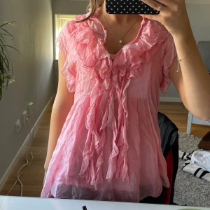 Rosa blus med volanger - Säljer en söt rosa blus eftersom den inte har kommit till användning. Finns ingen lapp på den så vet inte storlek men skulle säga S/M. Köpte för ca et år sedan men har inte använts någon gång så praktiskt taget ny💗💗