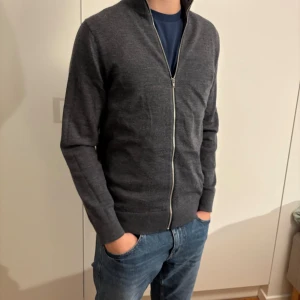 Riley Full Zip - Full zip från Riley i 100% merinoull. Fint skick förutom en defekt på kedjan (bild 2). Defekten gör att man inte kan dra upp dragkjedjan riktigt hela vägen men den påvärkar inget när man har tröjan som jag har den på bilden. 