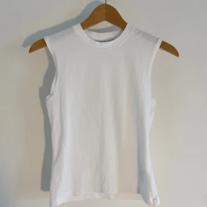 Vit ärmlös linnetopp från Weekday - Säljer en stilren vit linnetopp från Weekday i mjuk bomull. Toppen är ärmlös med rund halsringning och har en clean, enkel design som är lätt att matcha med allt. Perfekt för dig som gillar minimalistisk stil.