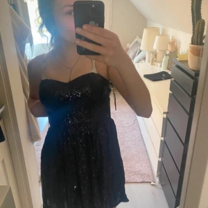 Svart paljettklänning från H&M - Supersnygg svart kort klänning från H&M med paljetter över hela tyget. Axelbandslös modell med hjärtformad urringning och figurnära överdel. Perfekt för dig som vill sticka ut och glänsa! Säljes pga garderobsrensning.