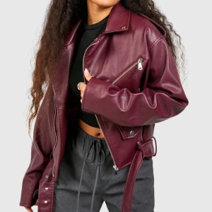 Bikerjacka stl 44 - Säljer en snygg vinröd bikerjacka från Boohoo med silvriga dragkedjor, bred krage och bälte i midjan. Jackan har flera fickor med dragkedja och detaljerade knappar på axlarna. Inköpt förra året men har aldrig blivit använd så den är som ny! Stl 44