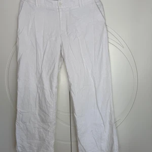 Vita lågmidjade linnebyxor från Hollister - Snygga vita linnebyxor från Hollister med låg midja och wide leg-passform. Byxorna har ett slags silkes tyg innanför vilket gör att byxan ej är genomskinlig.