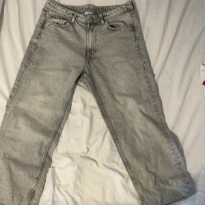 Grå raka jeans i storlek 164 - Snygga grå jeans med rak passform och klassisk femficksdesign. Jeansen har bälteshällor, knapp och dragkedja framtill. Perfekta för dig som gillar en enkel och stilren look. Materialet är slitstarkt denim i bomull.
