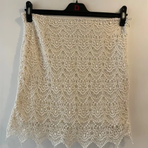 Virkad kjol  - En unik virkad kjol som är åt det krämvita hållet. Den har en underkjol men där virkningen går över underkjolen lite vid benen (se bild 2). Superfin och unik! Det är en dragkedja vid sidan så att den sitter på plats. Storlek 40 men jag har använt den och den sitter bra på mig, jag är normalt en storlek 38!