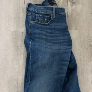 Replay blå jeans med klassisk tvätt - Snygga blå jeans från Replay med klassisk tvätt och diskreta slitningar. Jeansen har fem fickor, raka ben och tydliga sömmar. Perfekta för dig som gillar en tidlös och avslappnad stil. jeansen är uppsprättande där nere så kontakta mig om fler bilder osv