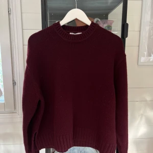 Vinröd stickad tröja från Zara - Vinröd stickad tröja från Zara med rund hals och ribbade muddar vid ärmslut och nederkant. Tröjan har en loose passform och är långärmad, perfekt för att hålla dig varm under kyliga dagar. Enkel och stilren design som funkar till många olika looks.