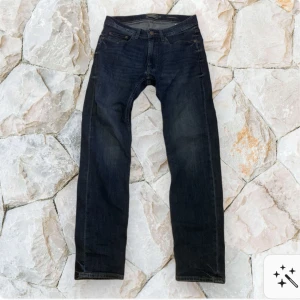 Dressman jeans  -   jeans i mörkblå tvätt med klassisk femficksdesign och bruna sömmar. Jeansen har en slim passform och är tillverkade i slitstarkt denim. Perfekta för dig som gillar en modern och stilren look. Asgoa sitter utmärkt !  Använda 2 gånger annars bara legat i garderoben 