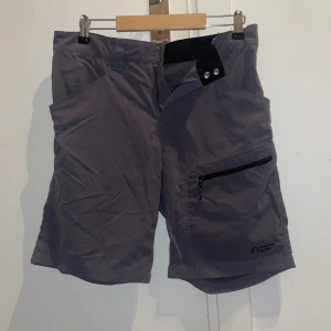Gråa shorts från North Bend - Snygga gråa shorts från North Bend med praktiska dragkedjefickor både fram och bak. De har en klassisk passform och är perfekta för utomhusaktiviteter. Materialet känns lätt och smidigt, vilket gör dem grymma för varma dagar.