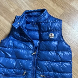 Moncler gui väst - Hej, säljer min Moncler gui väst i str 14 y då den inte har kommit till användning på det senaste. 