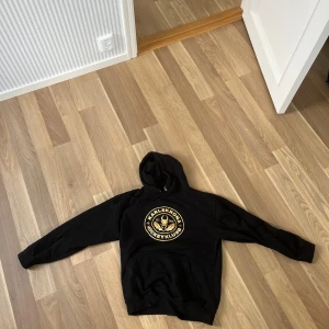 Svart KHK hoodie - Svart hoodie med guld KHK logga. 