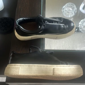 Svarta sneakers från Eytys, strl 37 - Svarta sneakers från Eytys i skinn med chunky vit sula, skorna har bra skick men sko snöret på skorna e lite sönder där av priset 
