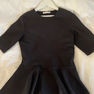 Svart kort klänning från Zara - Fin svart blus från Zara med volang längst ner på tröjan men slät upptill, använd endast en gång så de är i väldigt bra skick! Storlek S