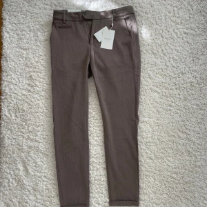 Bruna kostymbyxor Les Deux W29/L30 - Snygga störtsköna bruna kostymbyxor från Les Deux i modellen Como Suit Pants. Byxorna har en melerad brun färg. Perfekta för en clean och stilren look. Byxorna är köpta för flera år sen men aldrig använts. Dom är helt nya och har kvar lapparna. Anledningen är att de är för små för mig 😅
