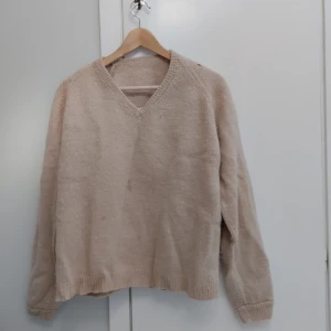 Beige stickad v-ringad tröja - Mysig beige stickad tröja med v-ringning och långa ärmar. Tröjan har ribbade muddar vid ärmslut och nederkant, perfekt för kyliga dagar. Den har lite fläckar och ett litet hål på baksida axel, därför det låga priset. Enkel och klassisk design som funkar till många olika stilar. Storlek står inte men passar S och M. Pris kan diskuteras! 